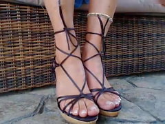 MILF shows her pretty feet in thin strappy wedge sandals.